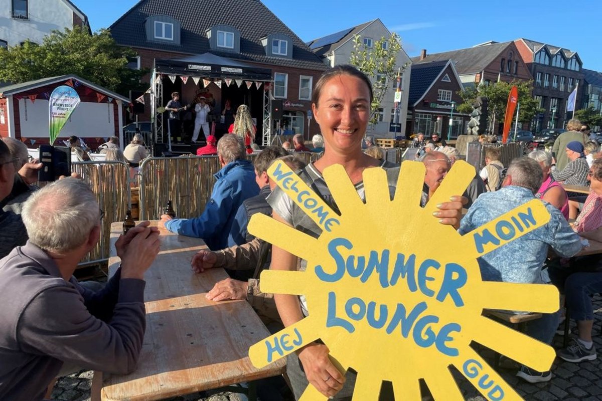 Stadtmarketing Koordinatorin Kira Sönksen freut sich über bestes Wetter bei der Bredstedter Summer Lounge. Foto: Felix Middendorf Eine Frau hält eine gelbe Sonne in der Hand