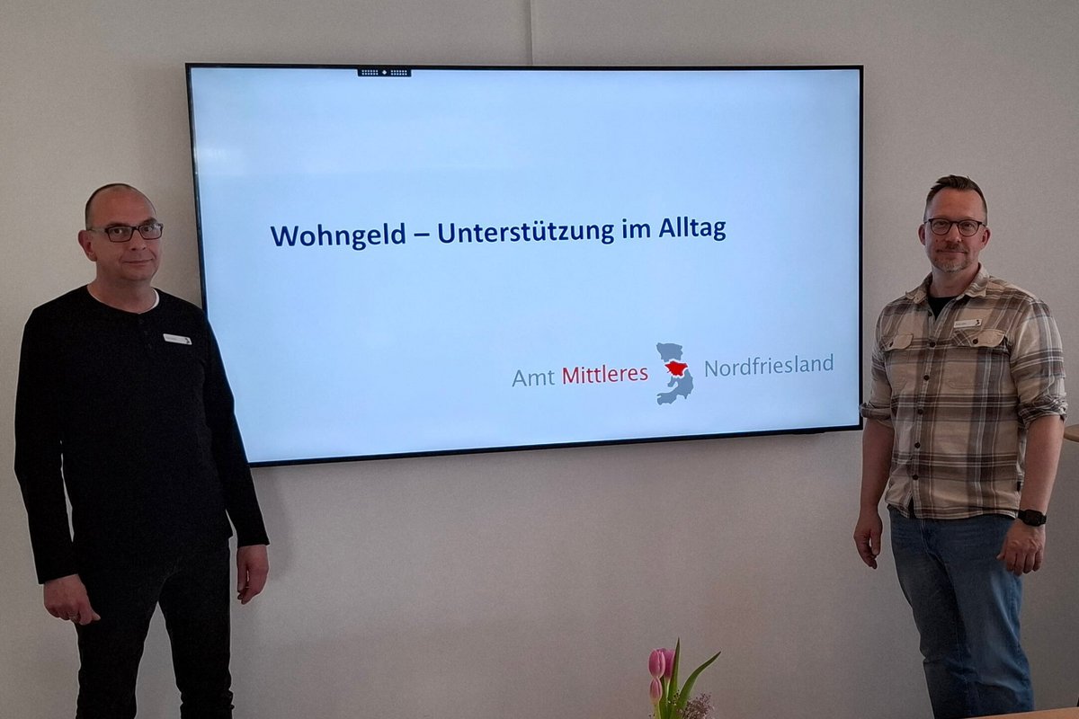 Arne Nissen (links) und André Höfer von der Wohngeldstelle des Amtes informierten im TondernTreff. Foto: Privat Zwei Männer stehen neben einem großen Bildschirm